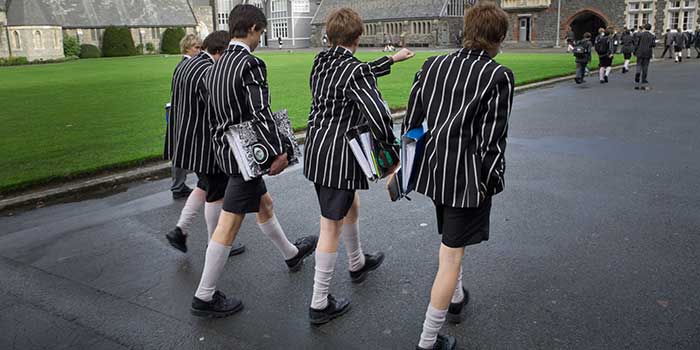 British school boys walking to class, carrying books while wearing shorts